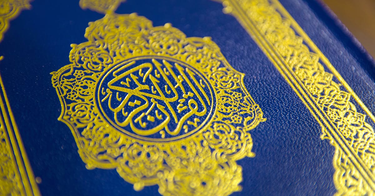 Close-up of intricate gold Quranic calligraphy on a blue cover, showcasing elegant Islamic design.