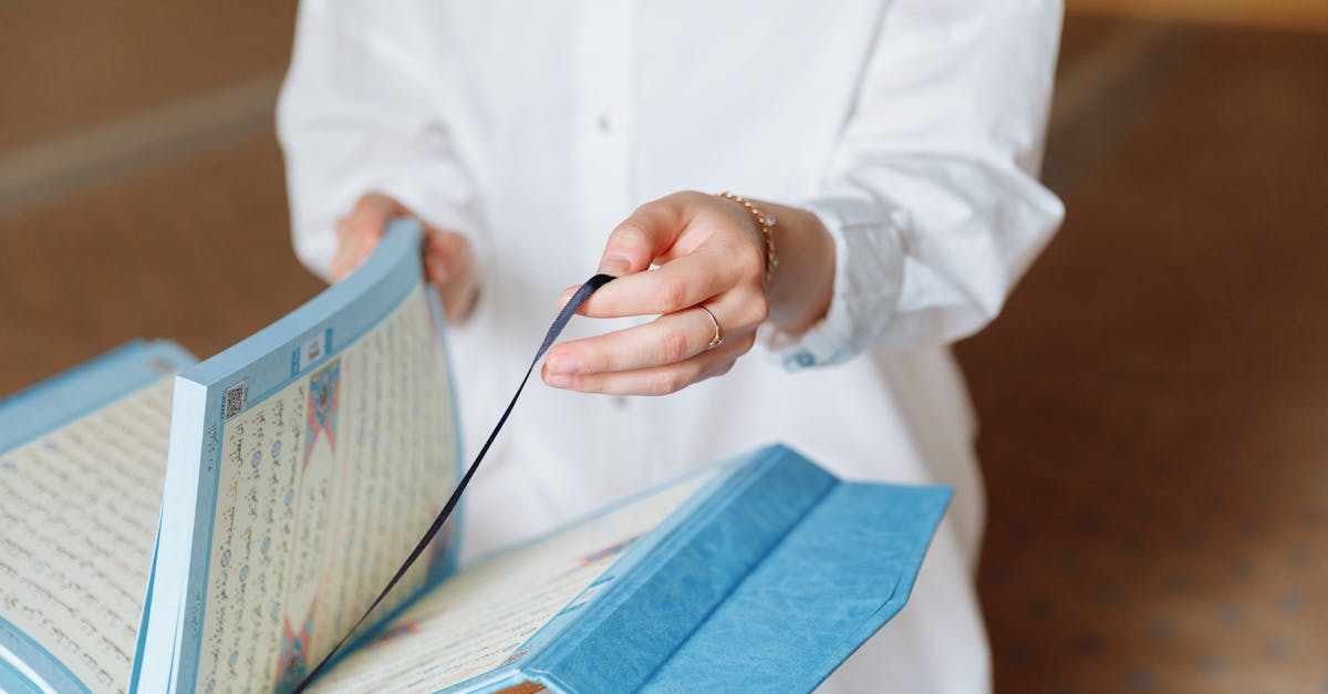 A person opening a Quran inside a mosque, depicting spiritual practice and Islamic faith.