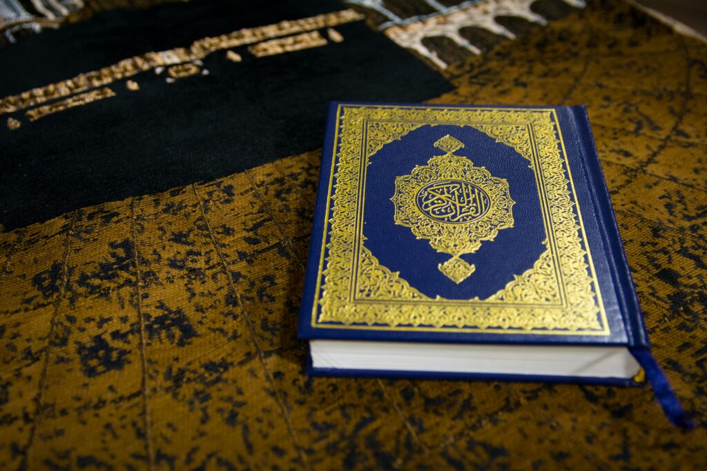 Beautiful Quran with intricate Arabic calligraphy on a textured prayer rug.